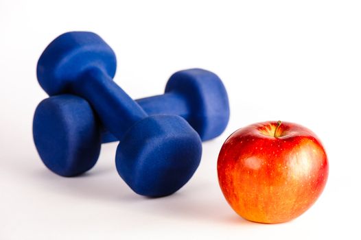 Blue dumbbells and red apple isolated on a white background