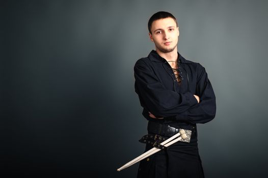 Young drummer in black scottish costume with drumsticks in his hand. Studio shot