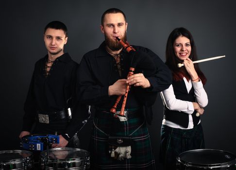 Musical band in scottish costumes with pipe and drums. Studio shot