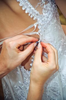 Hands helping to put on a wedding dress
