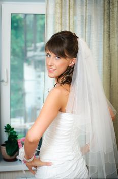 beautiful bride in white wedding dress put her hands on her hips. Stand and looking at camera.