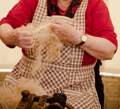 Photo of a elderly woman that spinning wool