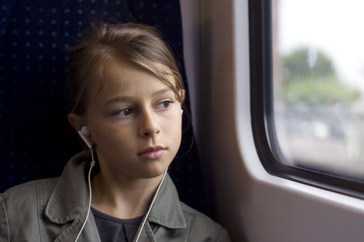 A child commuting on a bus or train, listening to music through headphones