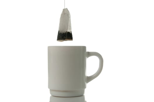 Tea bag over mug on a white background