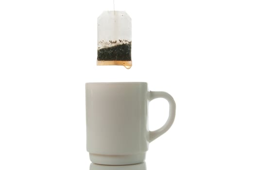 Tea bag over mug on a white background