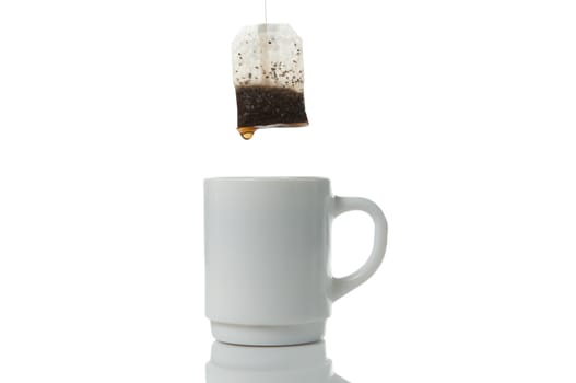 Tea bag over mug on a white background