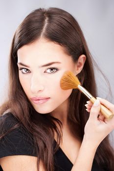 pretty young woman doing make up with powder brush