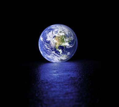 Glowing Planet earth on wet asphalt. Earth image provided by NASA.