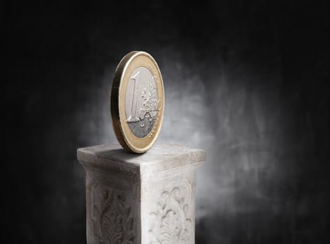 Euro coin on top of a plaster column.