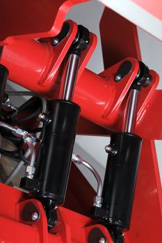 Industrial hydraulic cylinders on red machinery.