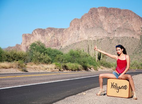 Beautiful young Hollywood hopeful hitching a lift on a desert road in California on a hot day.