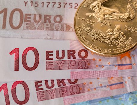 Solid gold coins contrasted with numbers on euro note suggesting debt problems