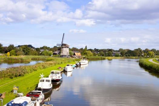 Dutch wind mill at river with little boats