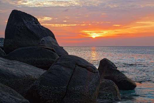 Big stones on an ocean coast against a sunset in tropics, Thailand