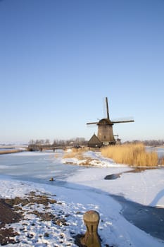 Windmill in winter time with snow and blue sky