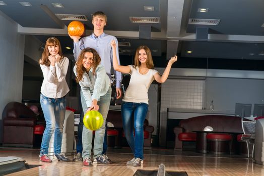 Group of young friends playing bowling, spending time with friends