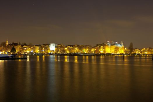 Amsterdam skyline at night with historic buildings and boats