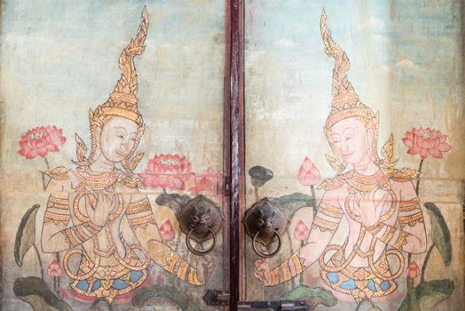 Very old vintage door with Buddha gods painting on it, take on a cloudy day