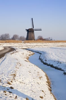 Windmill in winter time with snow, ice and blue sky