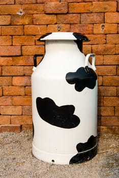 A large multi color metal milk container, taken on a sunny day