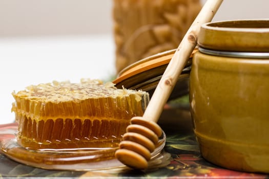 Sweet honey in pot with honeycomb and wooden stick