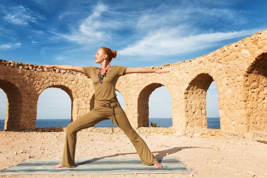 Beautiful woman practicing yoga outdoors against blue sky