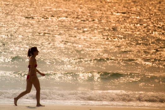 girl in red bigini walking on the beach