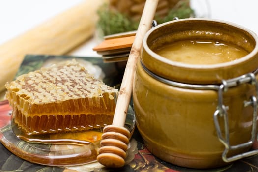 Sweet honey in pot with honeycomb and wooden stick