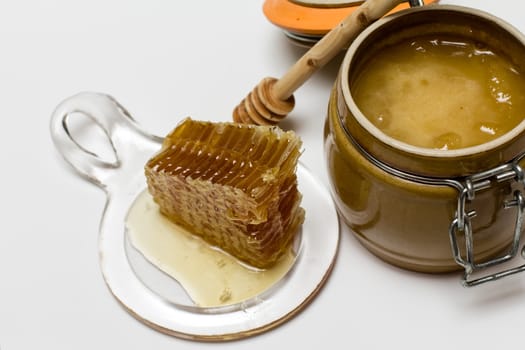 Sweet honey in pot with honeycomb and wooden stick