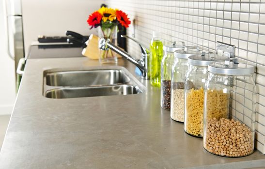 Modern small kitchen interior with glass jars on natural stone countertop