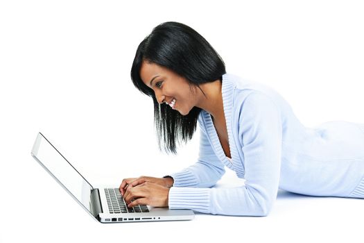Smiling black woman typing on computer laying on floor