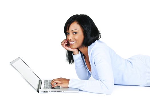 Smiling black woman using computer laying on floor looking at camera