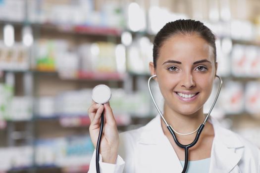 Young woman doctor holding stethoscope in pharmacy