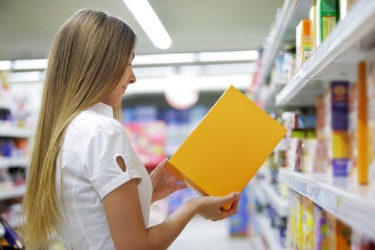 Woman checking food labelling in supermarket