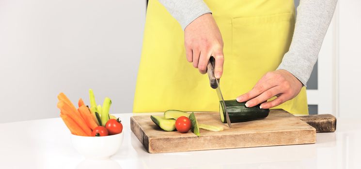 Woman cutting cucumber and vegetables