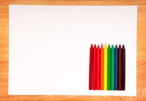Coloured Pencils Kit and Blank Paper on the Wooden Table