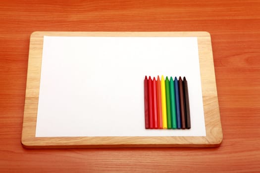 Coloured Pencils Kit and Blank Paper on the Wooden Table