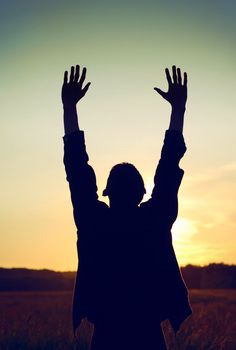 Vintage and Toned Photo of Praying Man on the Evening Sky Background