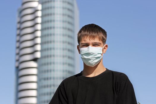 Serious Teenager in the Flu Mask on the City Street