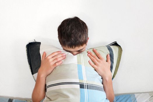 Sad Teenager sitting with pillow on the Bed in Home interior