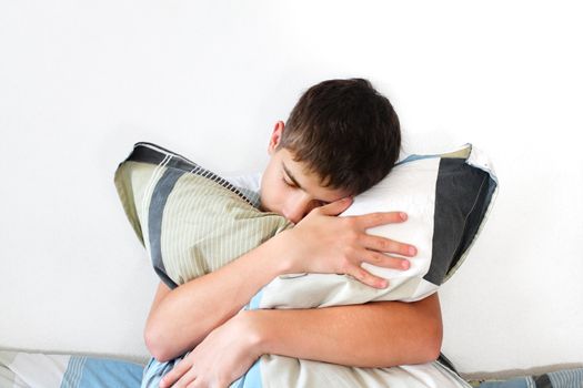 Sad Teenager sitting with pillow on the Bed in Home interior