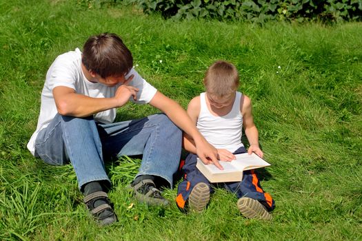 Little and Older Brothers reads a book in the Summer Park