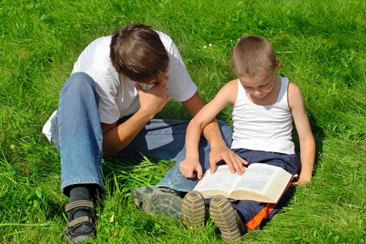 Little and Older Brothers reads a book in the Summer Park