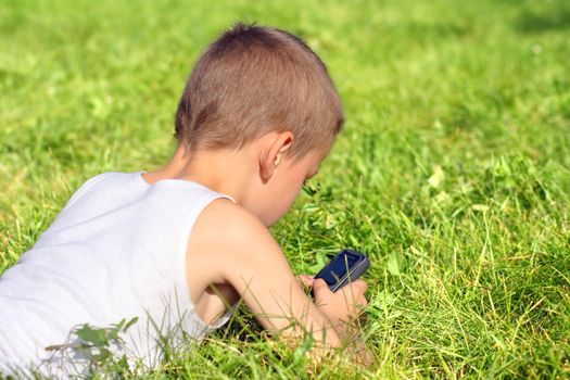 Little Boy with Mobile Gadget in the Summer Park