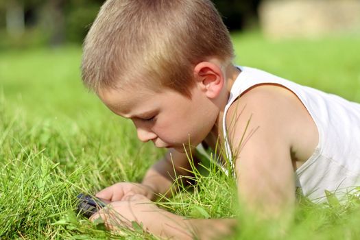 Little Boy with Mobile Gadget in the Summer Park