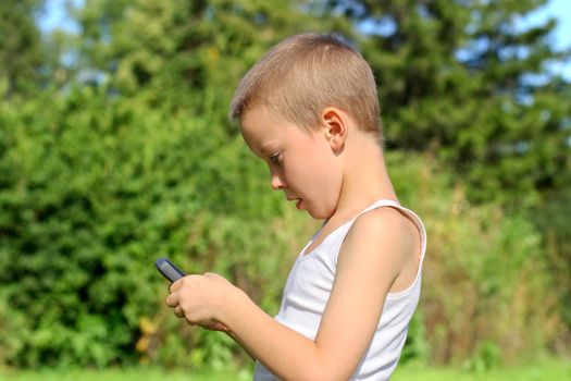 Little Boy with Mobile Gadget in the Summer Park