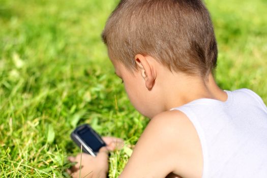 Little Boy with Mobile Gadget in the Summer Park