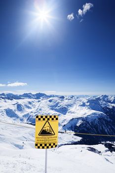 Snow ski resort caution sign on mountain under the sun