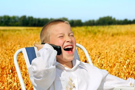 Cheerful Boy Laughing and calling on mobile phone in the wheat field