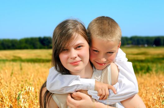 Happy little brother and sister portrait in the summer wheat field